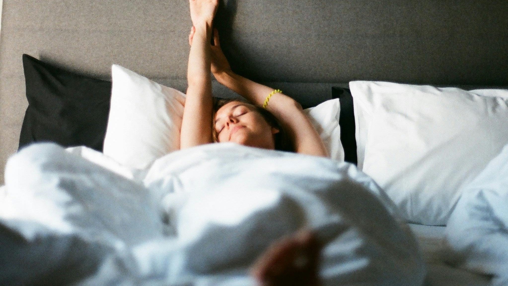 Lady stretching as she wakes in bed