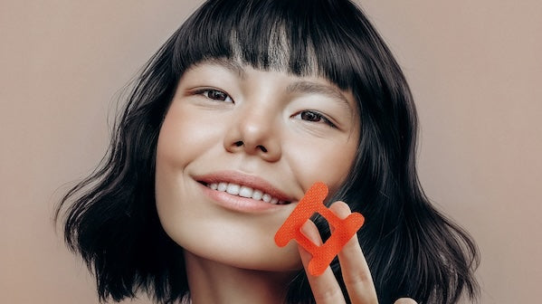 Lady with black bobbed hair holding a red kip&glow mouth tape and smiling