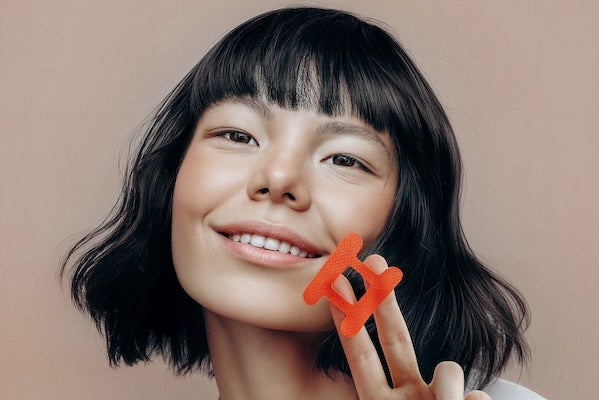 Lady with black bobbed hair holding a red kip&glow mouth tape and smiling