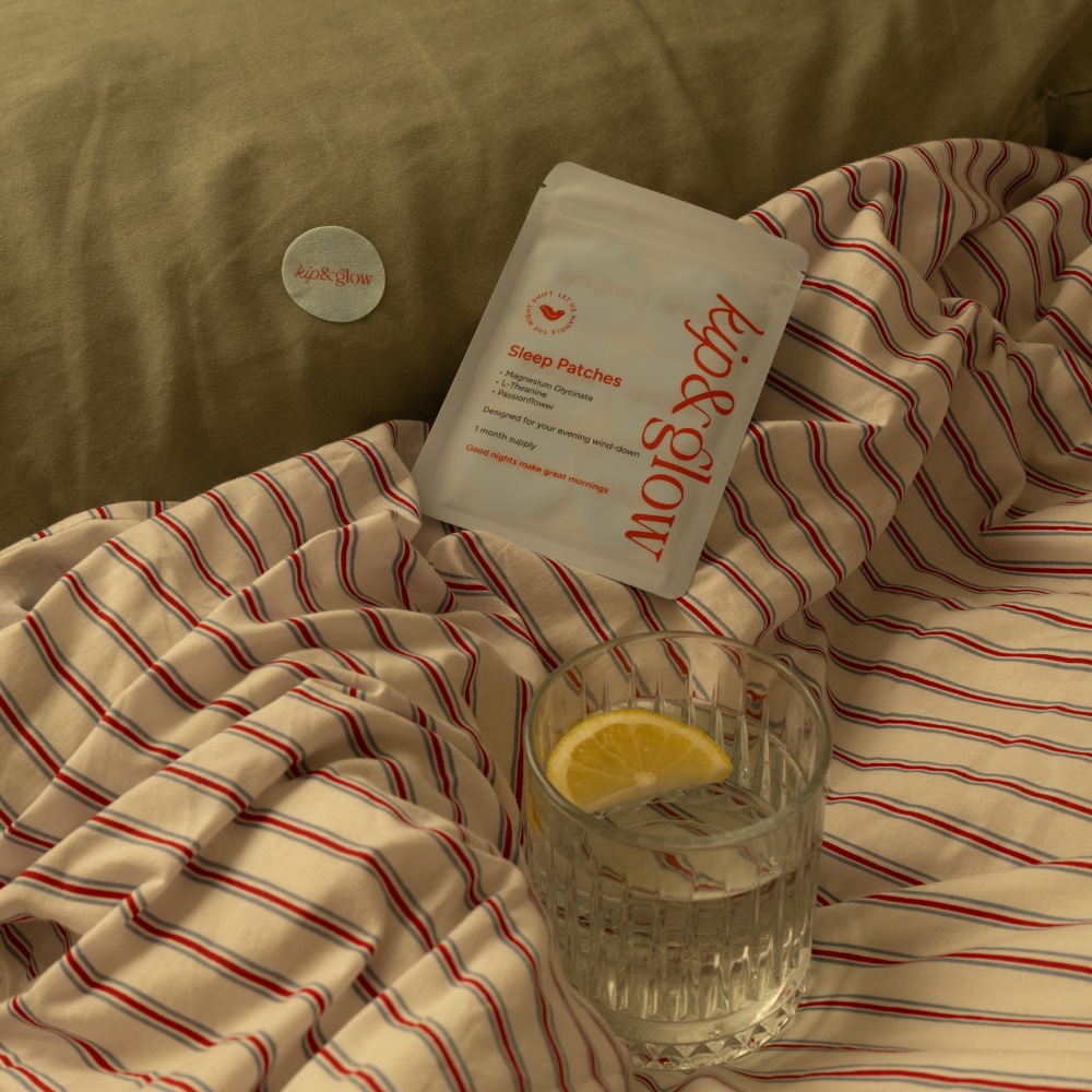 Sleep Patches on a striped blanket with a glass of water and lemon wedge.