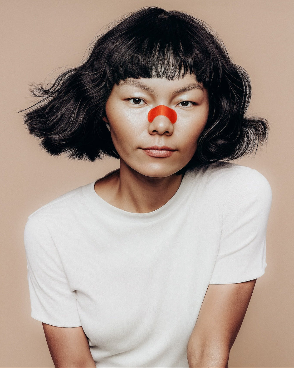 Person wearing a kip&glow nose strips and a white t-shirt on a beige background