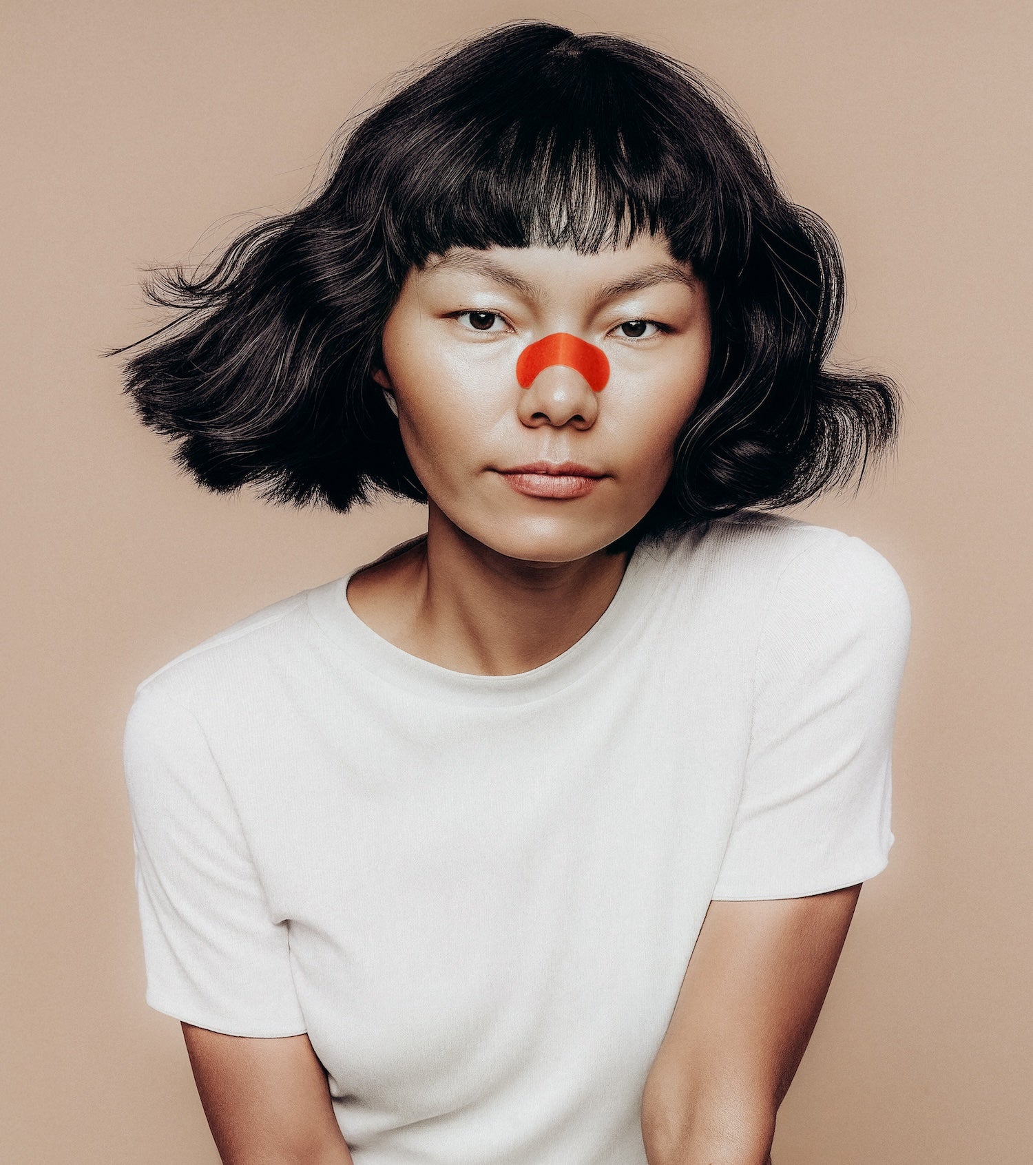 Person wearing a kip&glow nose strips and a white t-shirt on a beige background