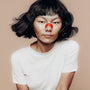 Person wearing a kip&glow nose strips and a white t-shirt on a beige background